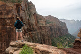Fototapeta Sawanna - Woman Stands On Rock Outcropping And Looks Out Over Zion Canyon