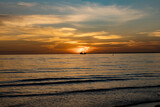Fototapeta Konie - Sailboat sunset fantasy with a silhouetted boat sailing along its journey against a vivid colorful sunset