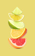 Stack of different citrus fruits on pale yellow background