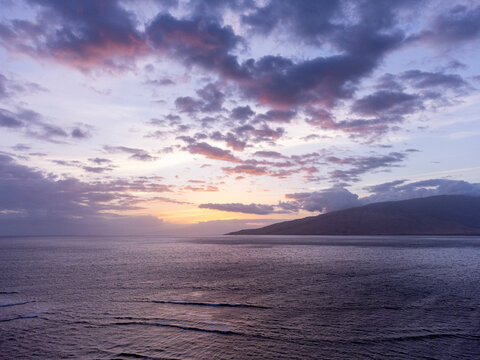 An aerial view of sunset light hitting mountain ridges on the west coast of Maui Hawaii as viewed from Kihei.
