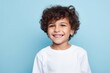 Portrait of a beautiful little boy with curly hair on a blue background