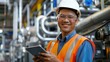© ttonaorh - Experienced engineer in hard hat using a tablet, standing in an industrial plant with machinery in the background