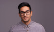 Young man, portrait and glasses in studio for eye care, vision and new frame with confidence on a gray background. Happy face of a young person or model in spectacles, eyewear and vision with lens