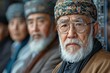 Elderly men with traditional headwear and spectacles in focused contemplation, culture-rich attire prominent.