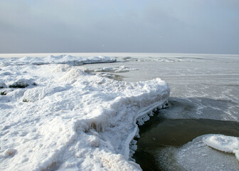 Wall Mural - winter landscape by the sea, snowy, interesting ice shapes on the sea shore, dunes covered with a white layer of shining snow