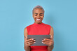 Young beautiful smiling African American woman holding electronic tablet in hands smiling watching funny video on internet or reading funny message from friend stands on turquoise background.