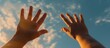 A hand is raised in the air with the sun shining on it. Concept of hope and positivity