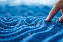 Finger Tracing Wave Patterns In Blue Sand