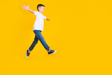 Wall Mural - Full length photo of carefree impressed boy wear white shirt jumping high arms sides empty space isolated yellow color background