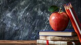 Fototapeta  - back to school: apple sitting atop a stack of books surrounded by supplies and stationery