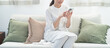 リビングのソファで携帯を持つミドルの日本人女性