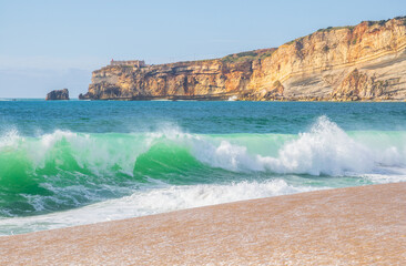 Wave and cliffs in Atlantic Ocean on the beach in Nazaré, Portugal