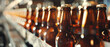 Amber beer bottles lined up on a conveyor belt, glowing warmly in an industrial setting.