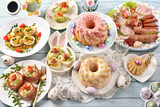 Fototapeta  - Traditional Easter breakfast with salads, deviled eggs, cold cuts and pastries on blue wooden table