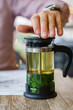Man making herbal tea by squeezing mint leafs in a teapot