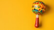© Larisa - Brightly painted maraca on a yellow background.
