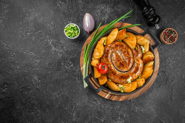 Wall Mural - delicious potatoes and baked sausage, Roasted potato and sausage dinner on a dark background. top view. copy space for text