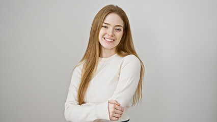 Poster - A beautiful, young caucasian woman in a white sweater smiling with crossed arms against a plain white background