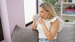 © Krakenimages.com - Young blonde woman drinking coffee sitting on sofa at home