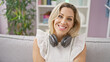 © Krakenimages.com - Young blonde woman wearing headphones sitting on sofa smiling at home