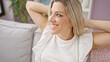 © Krakenimages.com - Young blonde woman relaxed with hands on head sitting on sofa at home