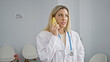 © Krakenimages.com - Young blonde woman doctor talking on smartphone at clinic waiting room