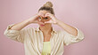 © Krakenimages.com - Young blonde woman smiling confident doing heart gesture with hands over eye over isolated pink background
