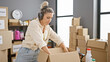 © Krakenimages.com - Young blonde woman volunteer packing clothes of cardboard box listening to music at charity center