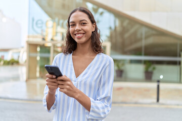 Canvas Print - Young african american woman smiling confident using smartphone at street