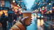 Close-up view of a hand holding a steaming hot coffee in a busy city street.