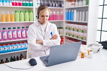 Poster - Young caucasian woman working at pharmacy drugstore using laptop skeptic and nervous, disapproving expression on face with crossed arms. negative person.