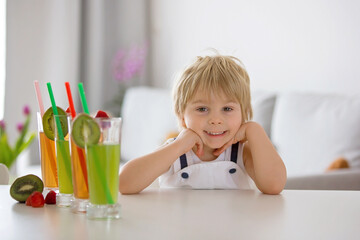 Poster - Cute toddler child, blond boy, drinking freshly made fruit juice at home