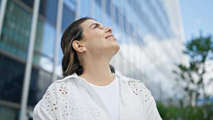 Wall Mural - Beautiful young hispanic woman smiling confident looking to the sky in the streets of Stockholm