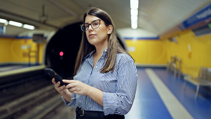 Sticker - Young beautiful hispanic woman waiting for the subway using smartphone in subway station of Madrid