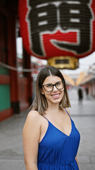 Poster - Beautiful hispanic woman donning glasses, flashing a cheerful smile at the senso-ji temple, immersed in japanese tradition, joyful latin adult exploring the rich culture of tokyo