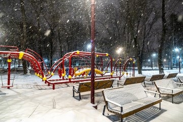 Wall Mural - Benches and swings in the park on a winter evening.