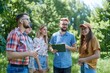Group of happy friends coworkers standing on grass in summer park on weekend and listening to manager with clipboard listing their tasks and explaining rules of outdoor team building, Generative AI