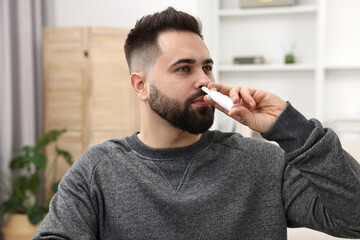 Sticker - Medical drops. Young man using nasal spray indoors