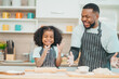 © chokniti - In a home kitchen, black father and his daughter bond over cooking a meal food, their laughter and love filling the air, embodying the joy of African American family life, Father's Day concept
