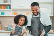 © chokniti - In a home kitchen, black father and his daughter bond over cooking a meal food, their laughter and love filling the air, embodying the joy of African American family life, Father's Day concept