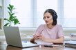 © Valerii Honcharuk - Young female college student in headphones studying using laptop computer for video chat