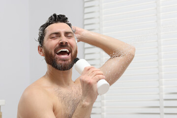 Poster - Happy man with bottle of shampoo singing in shower. Space for text