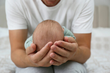 Wall Mural - Father holding his cute baby on bed at home, closeup