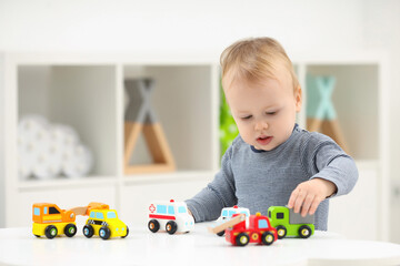 Sticker - Children toys. Cute little boy playing with toy cars at white table in room, space for text