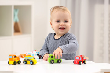 Sticker - Children toys. Cute little boy playing with toy cars at white table in room