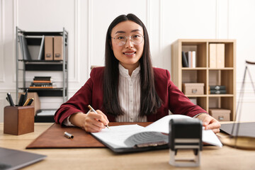 Wall Mural - Smiling notary signing document at table in office