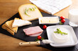 Cream Cheese spread on a black tray with ham, cheese, butter and loaves of bread. A glass of milk is also served on the table.