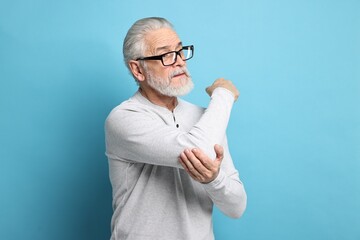 Wall Mural - Arthritis symptoms. Man suffering from pain in elbow on light blue background