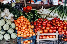 Colorful And Vibrant Assortment Of Fresh Vegetables And Fruits On Display At A Market Stall, Including Tomatoes, Broccoli, Peppers, Onions, And More