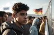 migration and refugees, immigration to germany, young men standing at the border fence. fictional location